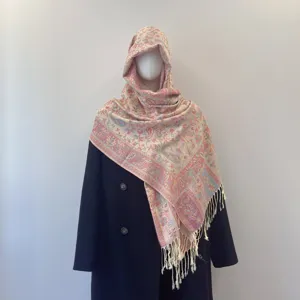 Close-up detail of ethnic paisley jacquard shawl with tassels displayed on a mannequin