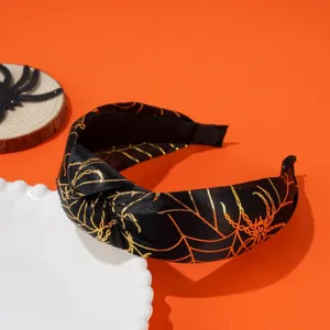 Detailed view of Halloween knotted headband with gold spider web pattern on black satin