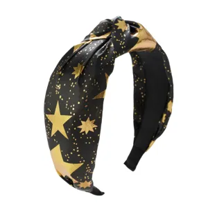 Close-up detail of black knotted headband featuring gold star and celestial patterns