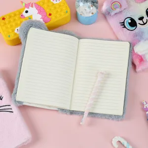 Nahaufnahme eines grauen, flauschigen Plüsch-Notizbuchs mit linierten Seiten und Stift auf Rosa.