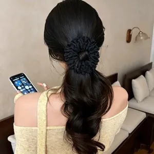 Primo piano della molletta per capelli in rete nera con pieghe mostra effetto chignon.