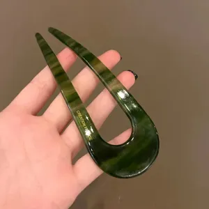 Detail view of green tortoise shell U shaped hairpin with French style engraving and smooth finish.