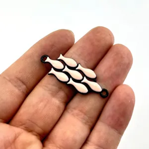 Nahaufnahme Detail von schwarzem Metall Emaille rosa Fisch Verbinder Anhänger Schmuck.