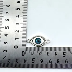 Detailed shot of vintage alloy evil eye pendant with double holes for DIY jewelry craft projects.