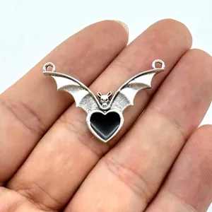 Close-up detail of the vintage silver bat wing heart pendant connector for DIY jewelry.