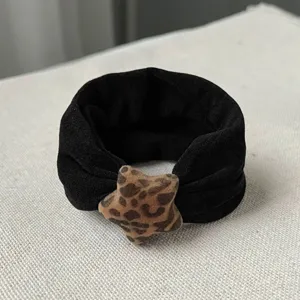 Detail view of a black velvet hair scrunchie with a cute leopard print plush star charm.
