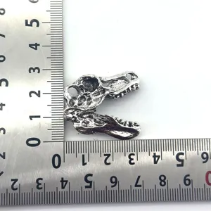Close-up detail view of the silver plated T-Rex dinosaur skull metal pendant with ruler.