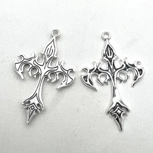 Primer plano detalle de colgante cruz punk gótico de metal, accesorio de joyería de plata antigua.
