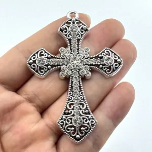 Gedetailleerd overzicht van grote versierde strass-kruishanger, vintage zilveren sieradenbevinding.