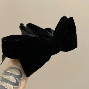 Detailed close-up view of a vintage black velvet bow hair clip with subtle sparkle for elegant hairstyles.