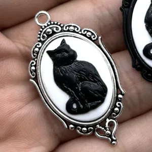 Primer plano detalle del colgante camafeo plata gato negro gótico vintage, accesorio tallado.