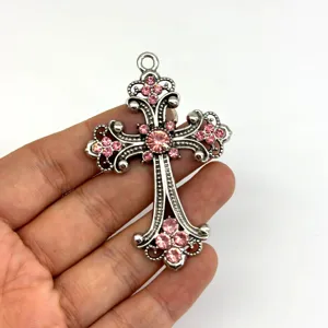 Detailaufnahme des Vintage Kreuz Anhängers aus Legierung mit funkelnden rosa Strasssteinen.