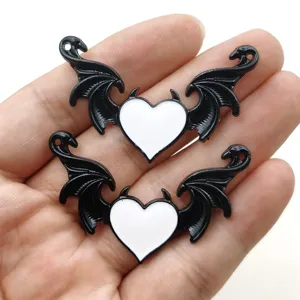 Primo piano di ciondoli in metallo con ali e cuore nero e bianco, perfetti per gioielli fai da te.