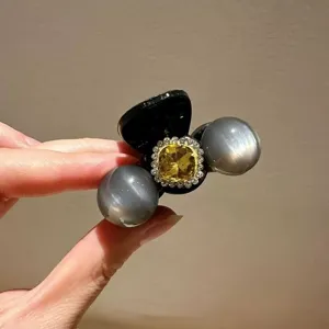 Detail shot of the elegant rhinestone hair claw clip with yellow crystal and grey pearl decor.