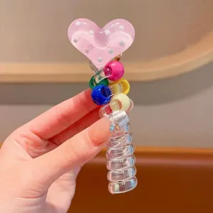 Close-up detail of cute clear telephone wire hair tie with pink polka dot heart and colorful beads.