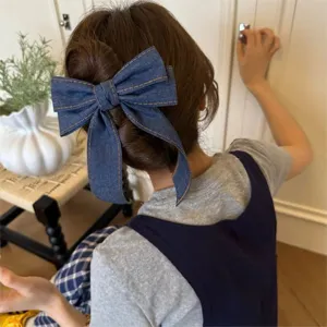 Gros plan detaille d'une pince a cheveux noeud en denim bleu retro stylee sur les cheveux.
