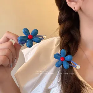 Close-up detail of blue flower hair clip with red center and rhinestone for sweet girls.