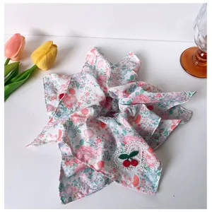 Detailed close-up view of floral scrunchie with lace heart and cherry embroidery on white desk.