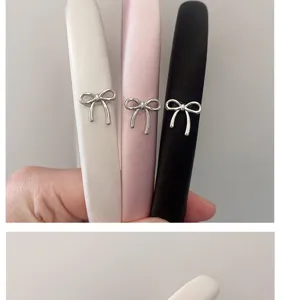 Close-up detail of satin headbands featuring delicate silver bow charms in multiple colors.