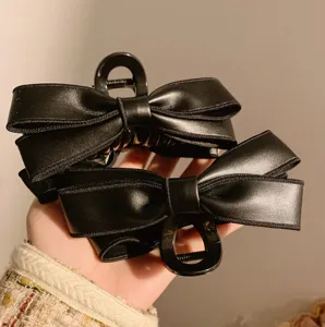 Close-up view of the black PU leather bow hair claw, showcasing fine texture and design.