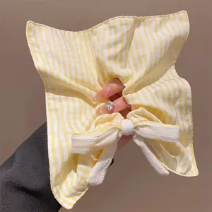 Nahaufnahme Detail der gelb-weißen gestreiften Stoff Haarschleife, elegantes Spitzendesign.