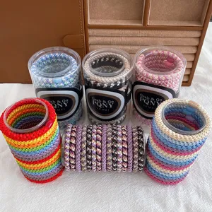 Detail view of colorful braided hair ties in clear jars, high elastic basic hair bands for women.