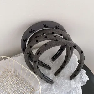 Detail view of grey fabric headband with cute bow and dot print, stylish hair accessory close-up.
