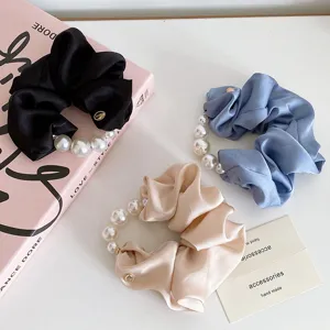 Detailansicht von stilvollen Satin-Perlen-Haargummis in drei schicken Farben für Damen.