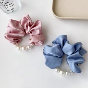 Nahaufnahme elegante Satin Haargummis mit großen weißen Perlen in Rosa und Blau.
