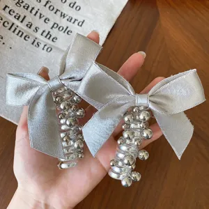 Elastico per capelli con fiocco argento e spirale trasparente con perle metalliche.