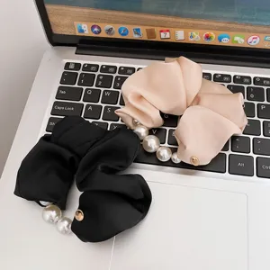 Detailaufnahme von Perlen-Satin-Haargummis, elegante schwarze und beige elastische Haarbänder.