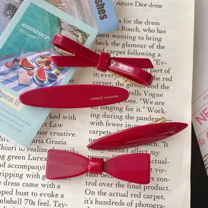 Detail of wine red glossy resin bow and oval hair clips on retro paper showing sweet style.