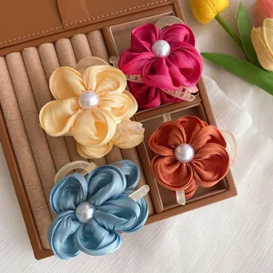 Nahaufnahme einer Stoffblumen Haarklammer mit Perlenmitte, elegante Frisur für hinten.