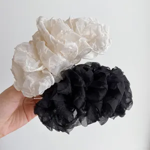 Detailed close-up showing large sheer organza bow hair claw clips in beige and black.