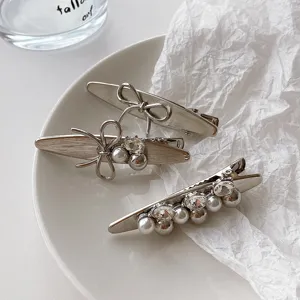 Silver brushed metal bow hair clip detailed view, featuring sparkling rhinestones and pearls.