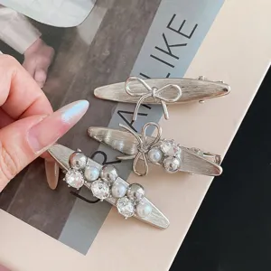 Detailed view of silver brushed metal bow hair clips with pearls, chic cute hairpin.