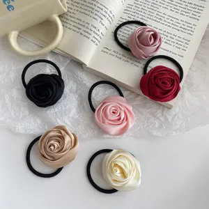 Detailed shot of satin rose hair ties in various colors, showcasing fabric flower texture.