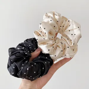 Close-up of satin polka dot hair scrunchies, showing soft fabric texture and elastic band.