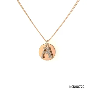 Detail view of a rose gold layered necklace featuring a coin pendant with a sparkly letter A.