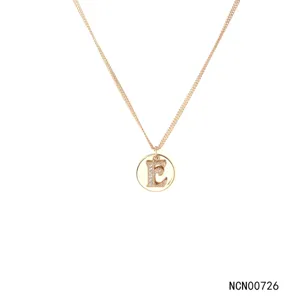 Close-up details of the double chain crystal pave letter E pendant necklace in shiny gold.
