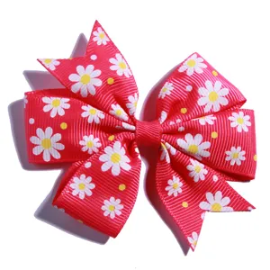 Macro view of red grosgrain hair bow with white and yellow daisy floral pattern print
