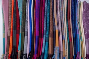 Macro view of multiple colorful paisley pashmina scarves with elegant tassel details