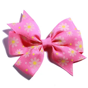 Detailed view of a pink grosgrain hair bow featuring yellow daisy floral prints