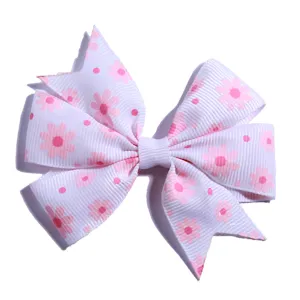 Detailed macro view of white grosgrain ribbon hair bow with pink daisy floral prints