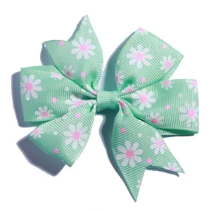 Detail view of a mint green grosgrain hair bow featuring white and pink daisy prints