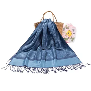 Elegant blue paisley jacquard pashmina scarf with fringe tassels shown on woven bag