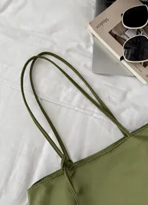 Green tote bag detail with slim double straps, minimalist style, premium everyday aesthetic.