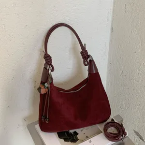 Détail de sac porté épaule en suédine bordeaux, sac hobo vintage avec poignée nouée.