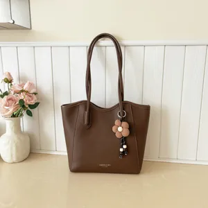 Braune Damen Umhängetasche Detailansicht mit Blumenanhänger und geräumigem Innenraum.