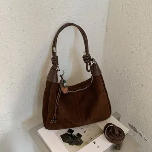 Vue détaillée du sac porté épaule marron en suédine avec texture et joli petit pendentif.